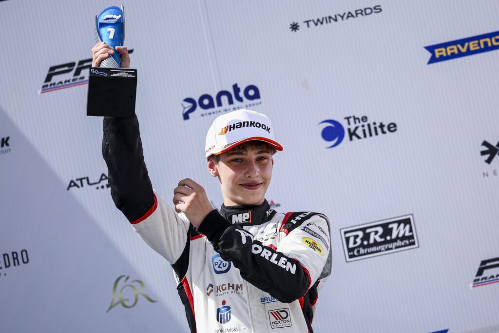 Maciej Gładysz na podium, trzymający nagrodę.